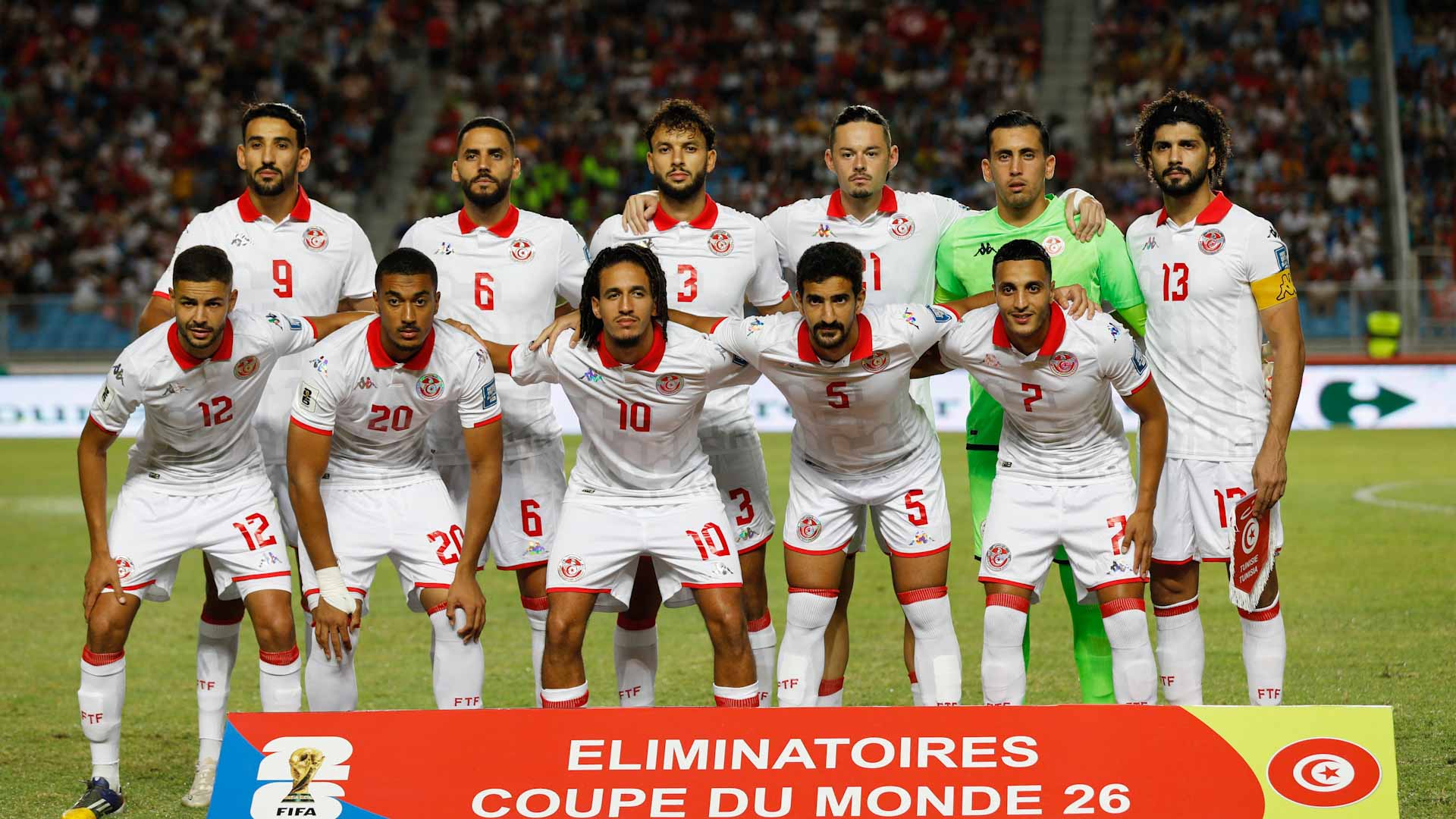 Tunisia to FIFA World Cup 26™ Tunisia national football team posing together before a FIFA World Cup 2026 qualifier match, wearing white and red uniforms on the field.