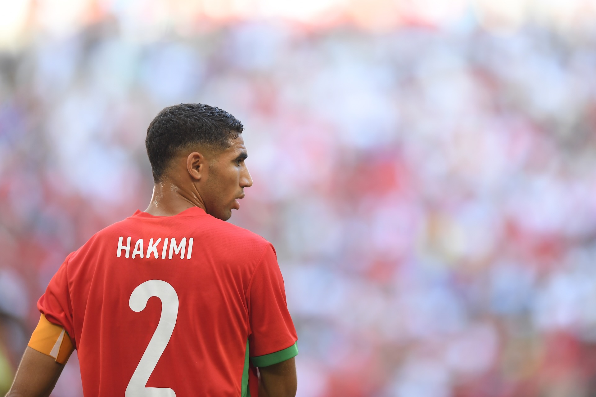 Achraf Hakimi in Action for Morocco National Football Team Achraf Hakimi wearing a red Morocco football jersey with number 2 during an international match, seen from the back.