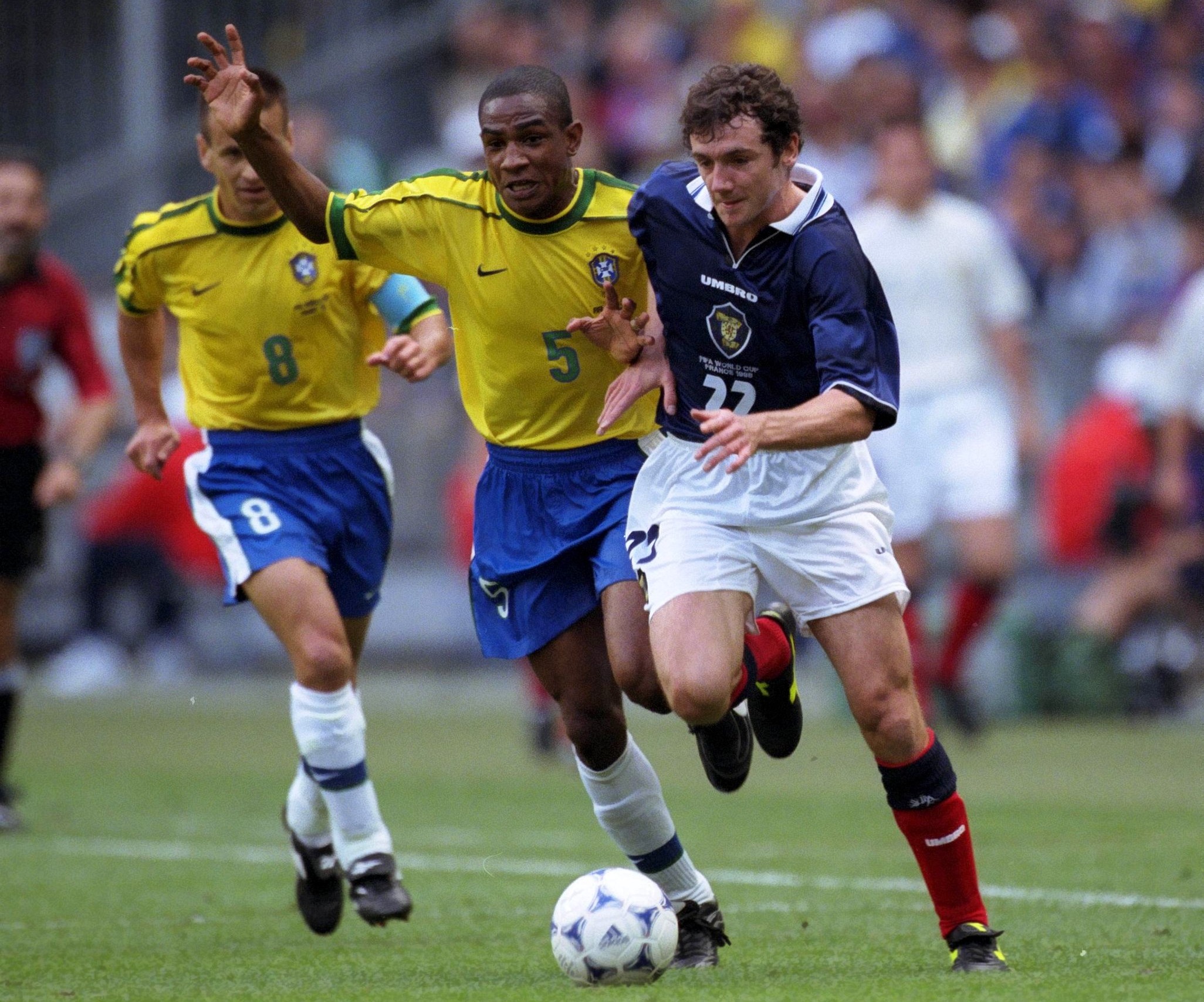 Brazil and Scotland football players battling for possession during an international match, with intense action on the field.