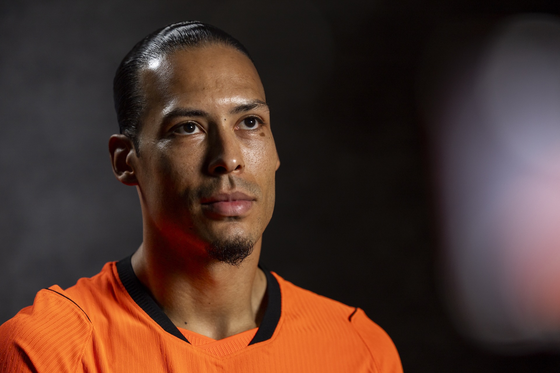 Netherlands football player in an orange jersey looking focused in a portrait session.