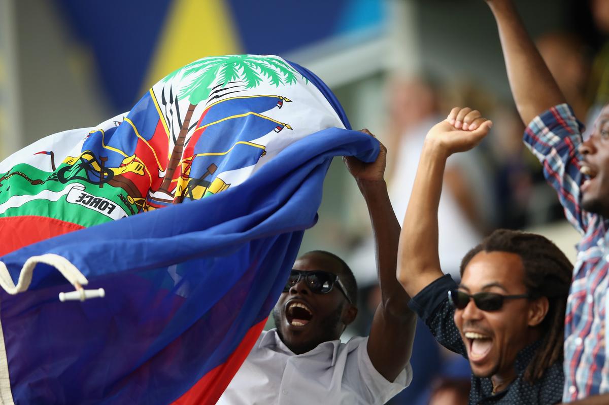 Haiti fans cheering and waving the Haitian flag in a stadium during a FIFA World Cup match Right-to-Tickets